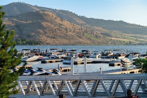 A marina with boats docked, a pier, and a hilly landscape in the background.