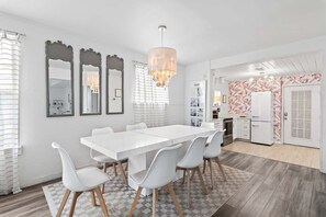 A modern kitchen with white cabinetry, a dining area with a white table and chairs, and a chandelier.