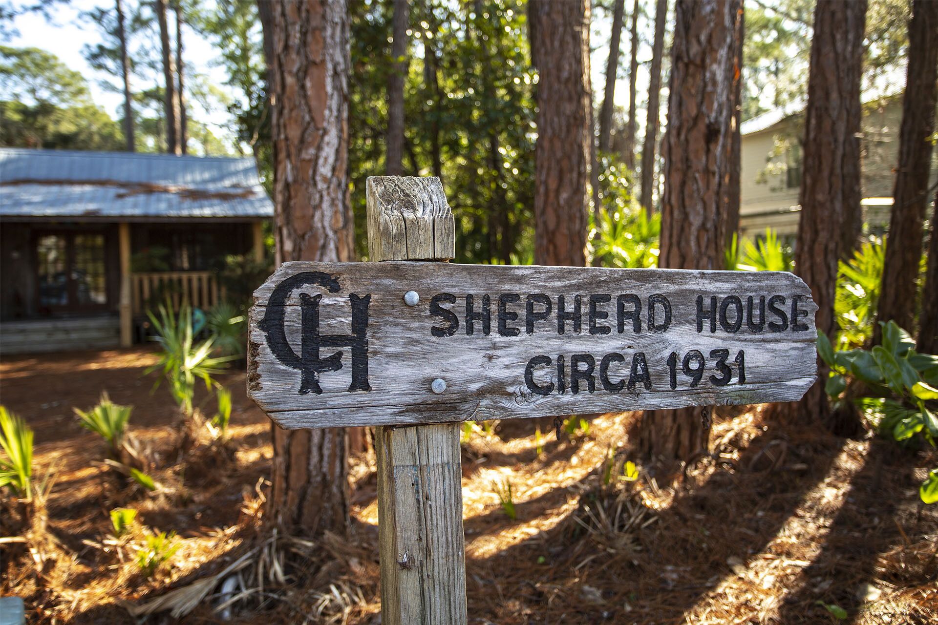 A wooden signpost with the inscription "Shepherd House circa 1931" in a forested area.