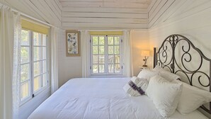 Een slaapkamer met een bed, een raam en een aan de muur hangend schilderij.