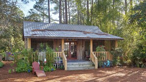 Een landelijke chalet met een houten veranda, een kleine voortuin en een brievenbus.