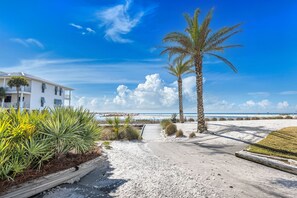 A beachfront property with a white building, palm trees, and a clear view of the ocean.