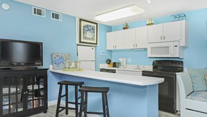 A compact kitchen with a central island, white cabinets, a microwave, and a stove. - QUAINT 1 BDRM!! RECENTLY UPDATED! STEPS ACROSS THE PARKING LOT TO BEACH!! (Fort Walton Beach)