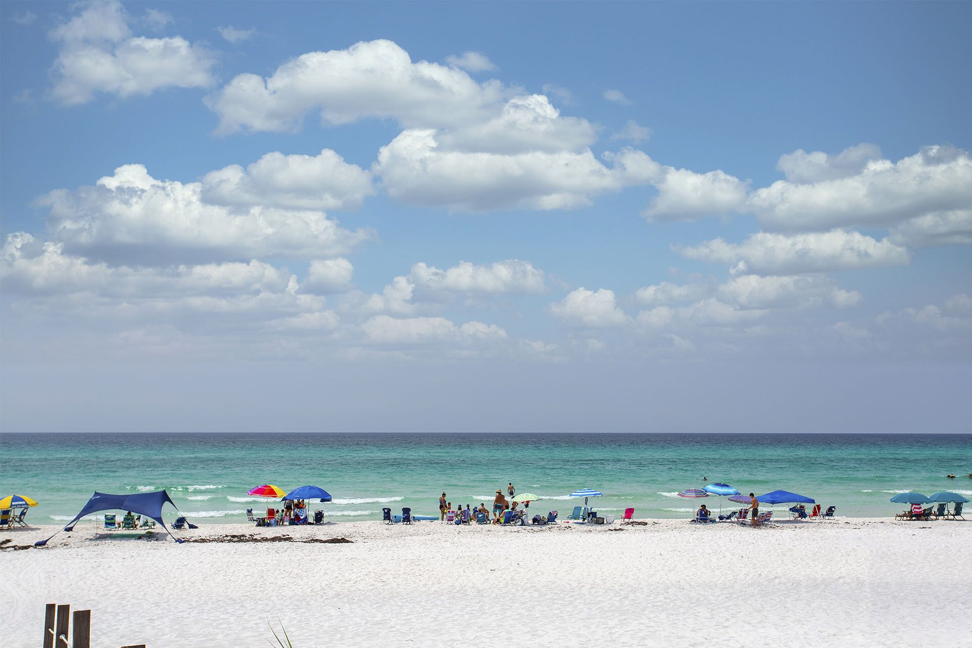 A beach with umbrellas and beach chairs, a clear sky, and the ocean.