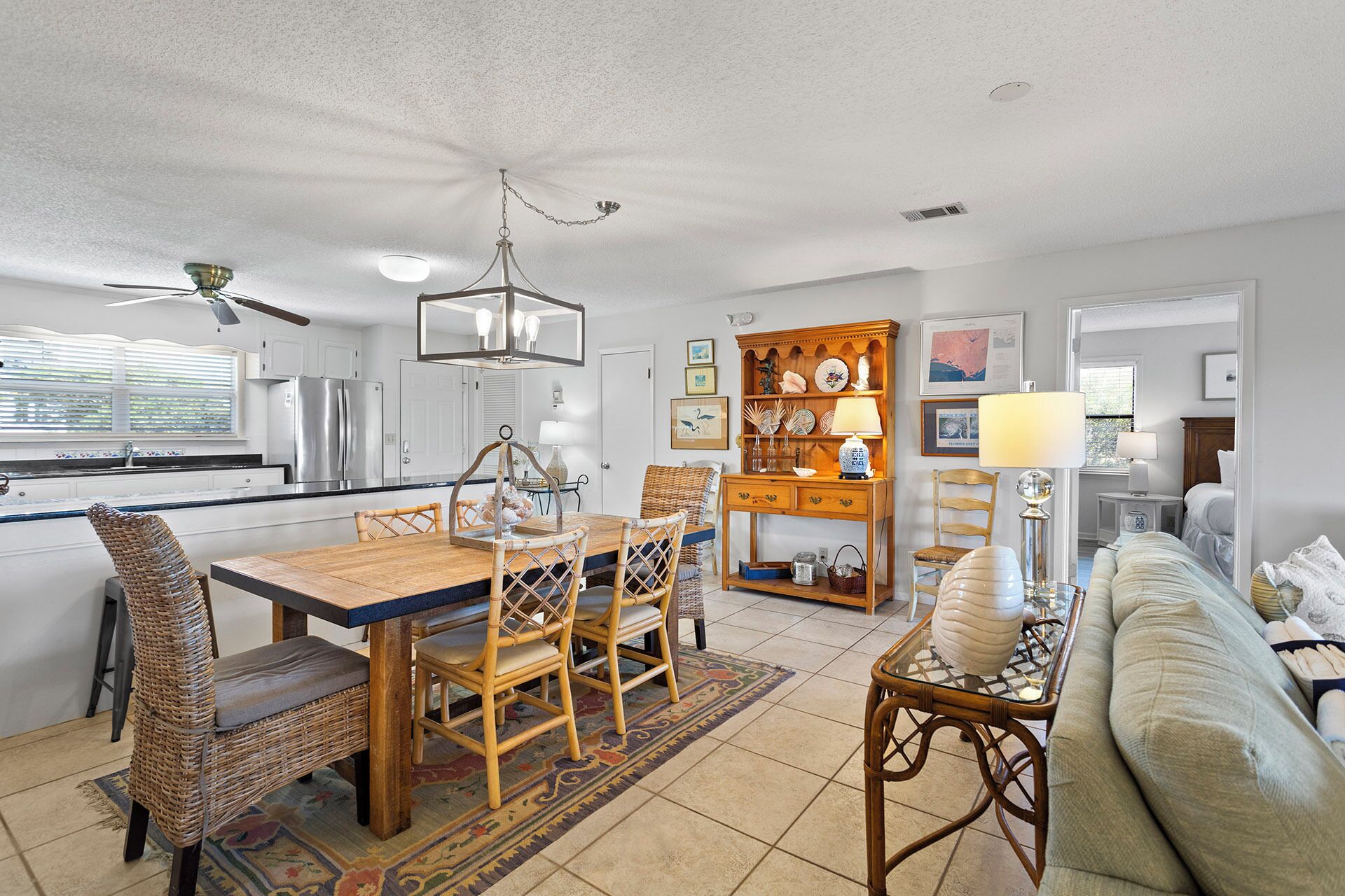 A spacious kitchen with modern appliances, a dining area with wicker furniture, and a cozy living room with a sofa and a coffee table.