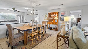 Eine geräumige Küche mit modernen Geräten, ein Essbereich mit Korbmöbeln und ein gemütliches Wohnzimmer mit Sofa und Couchtisch.