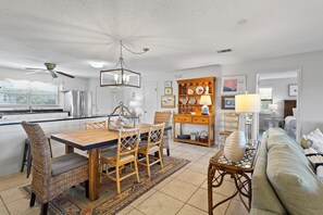 A spacious kitchen with modern appliances, a dining area with wicker furniture, and a cozy living room with a sofa and a coffee table.