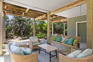 An outdoor patio with wicker furniture, a wooden table, and a swing.