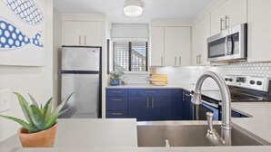 A modern kitchen with white cabinets, a stainless steel refrigerator, a microwave, an oven, and a sink with a modern faucet. - Grayton Beach Villas 103 - Gulf View, Grayton Beach, 30A, Steps to the Sand! (Grayton Beach)