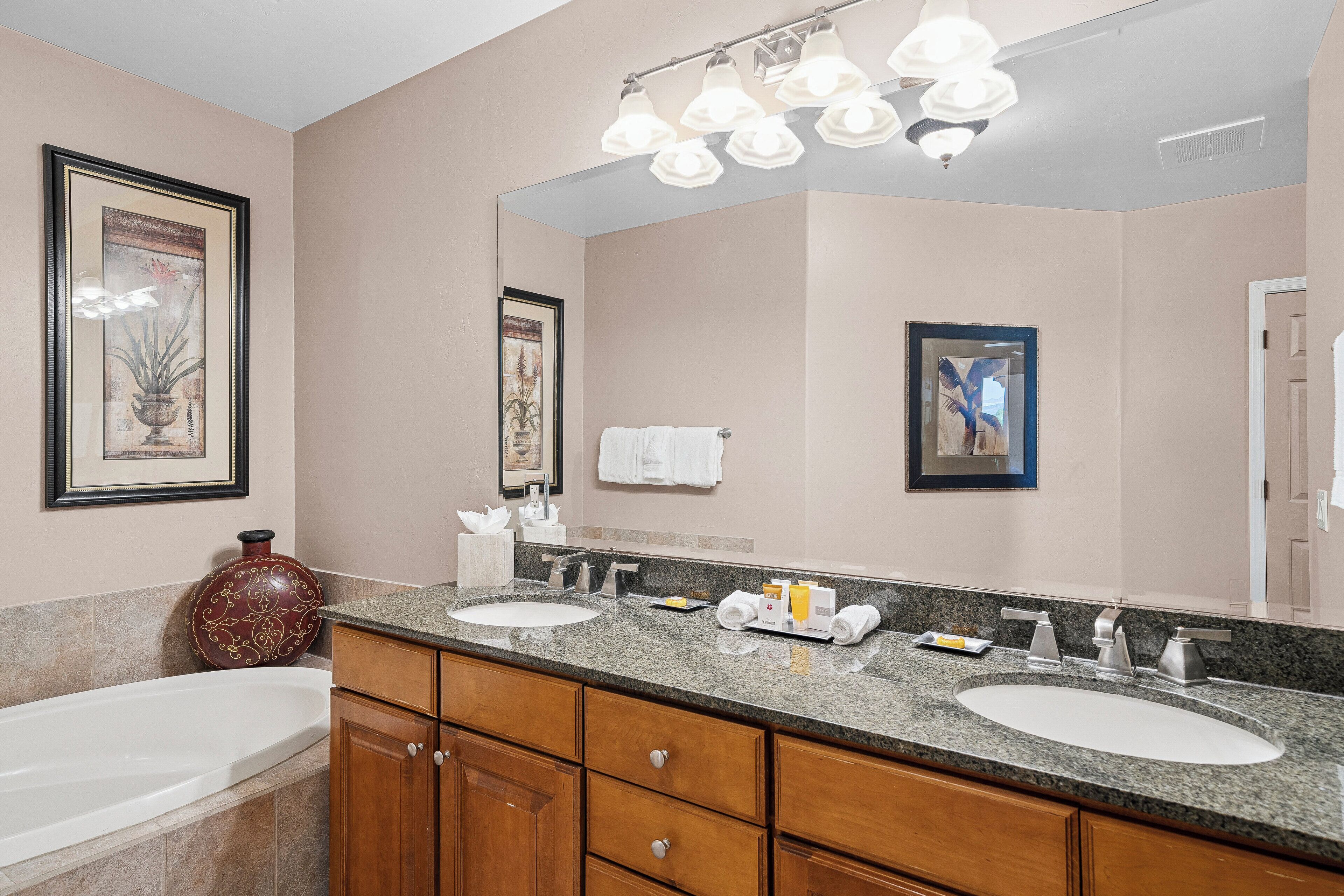 A bathroom with two sinks, a large mirror, and a vanity with wooden cabinets.