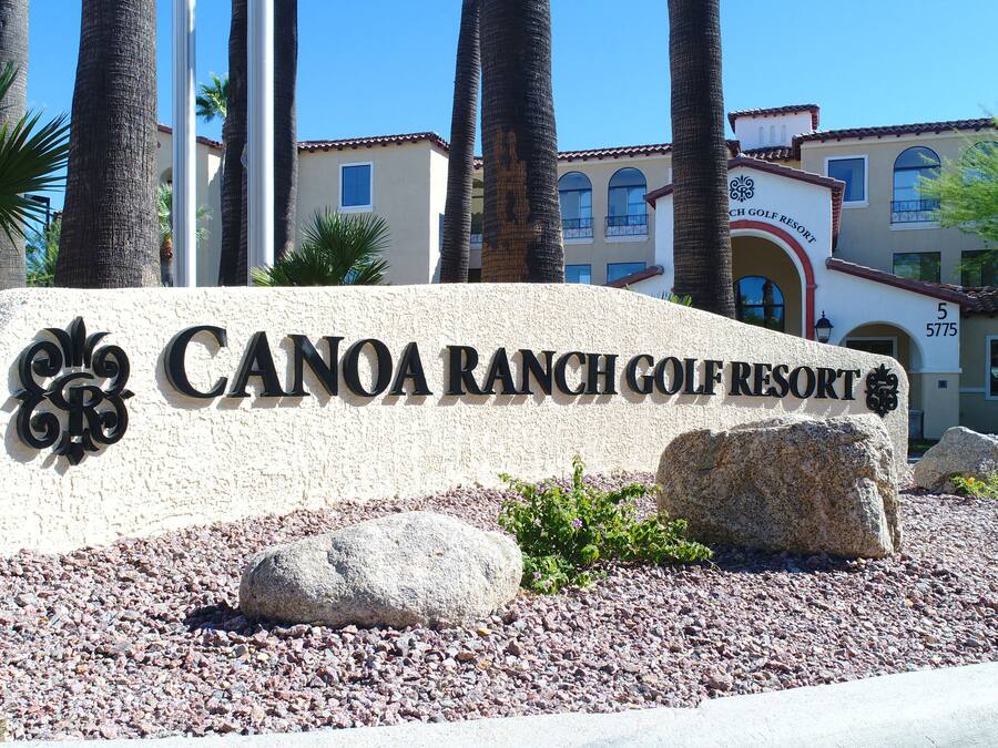 A sign for Canoa Ranch Golf Resort with a clear view of the building in the background.