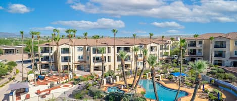 A resort with multiple-story buildings, a swimming pool, and palm trees.