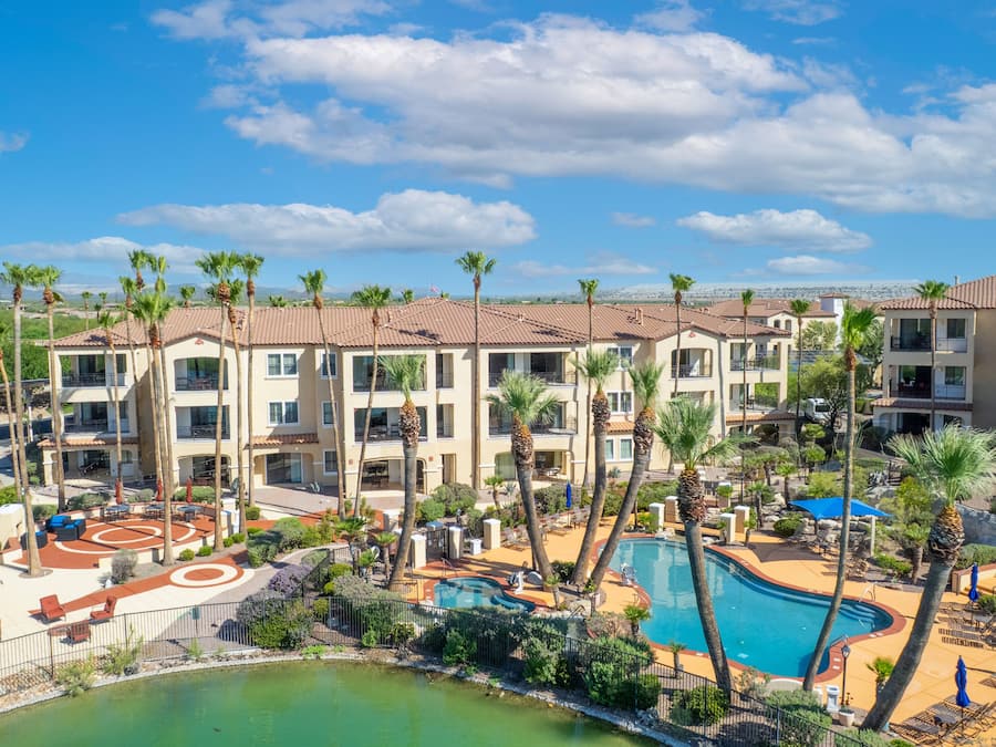 A resort with multiple-story buildings, a swimming pool, and palm trees.