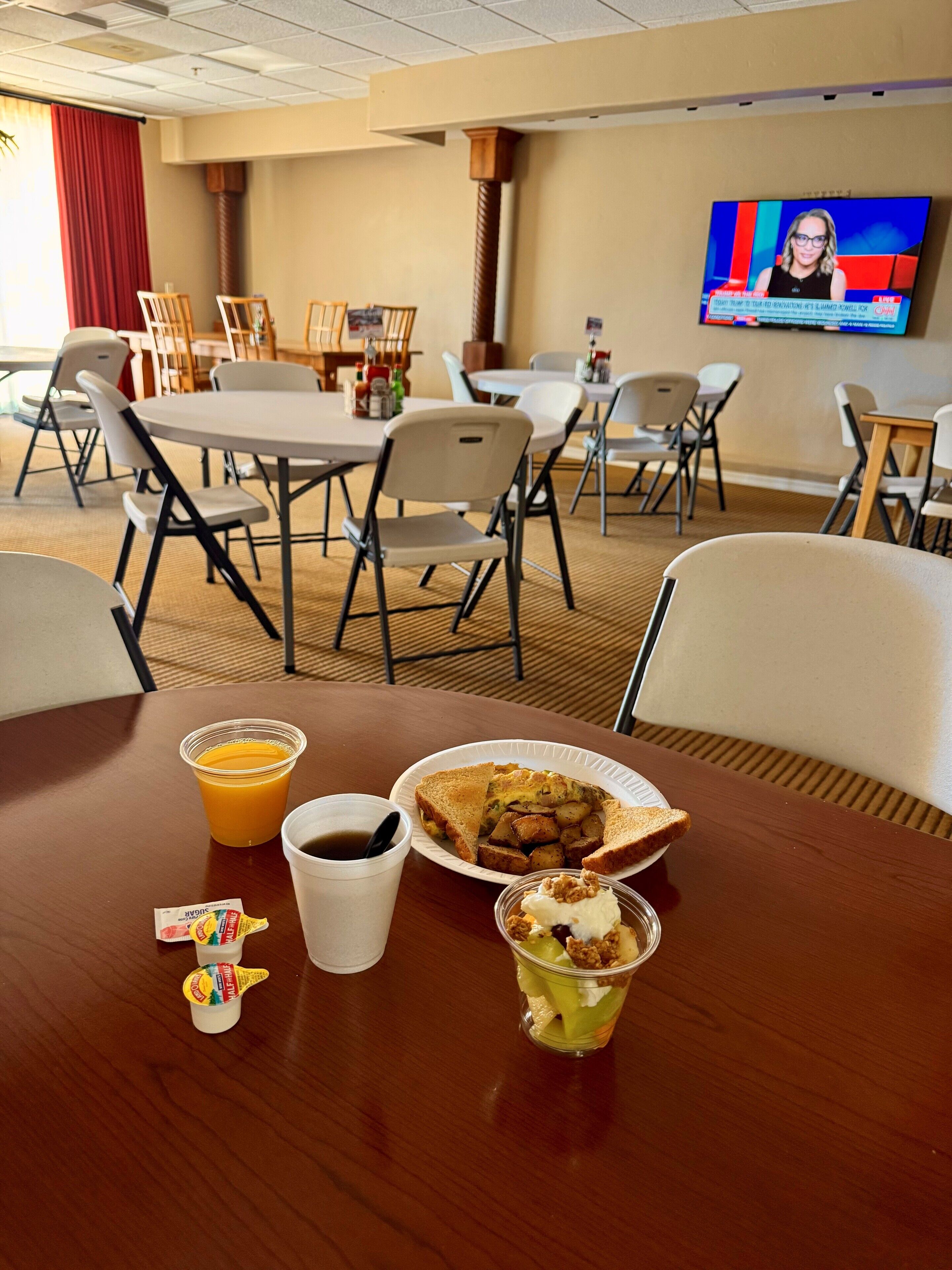 A conference room with a table set for a meal, including a plate of food, a drink, and condiments.