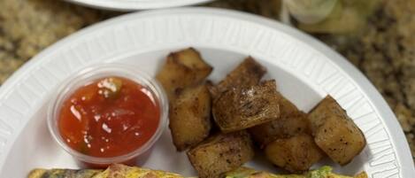 A breakfast plate with pancakes, hash browns, and a fruit salad.