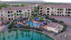 A resort with multiple buildings, a swimming pool, and palm trees.
