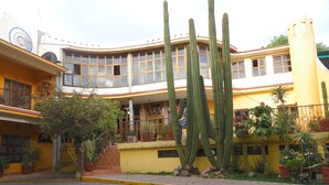 Un edificio con fachada amarilla, varias ventanas y un balcón con macetas.