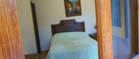 A bedroom with a wooden headboard, a bed with a striped bedspread, a nightstand, and a painting on the wall.
