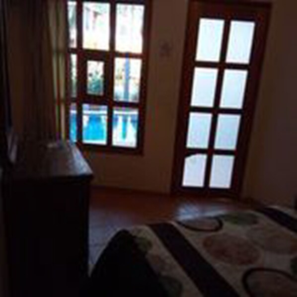 A room with a large window, a wooden door, and a bed with a patterned bedspread. - Hotel Plaza del Sol (Malinalco)