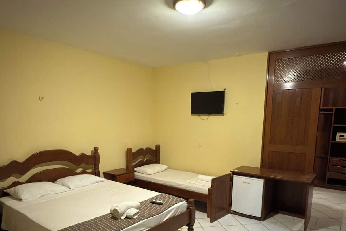 A room with two beds, a desk, a wardrobe, and a ceiling light.