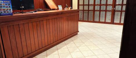 Una zona de recepción con un mostrador de madera, una computadora y un área de asientos.