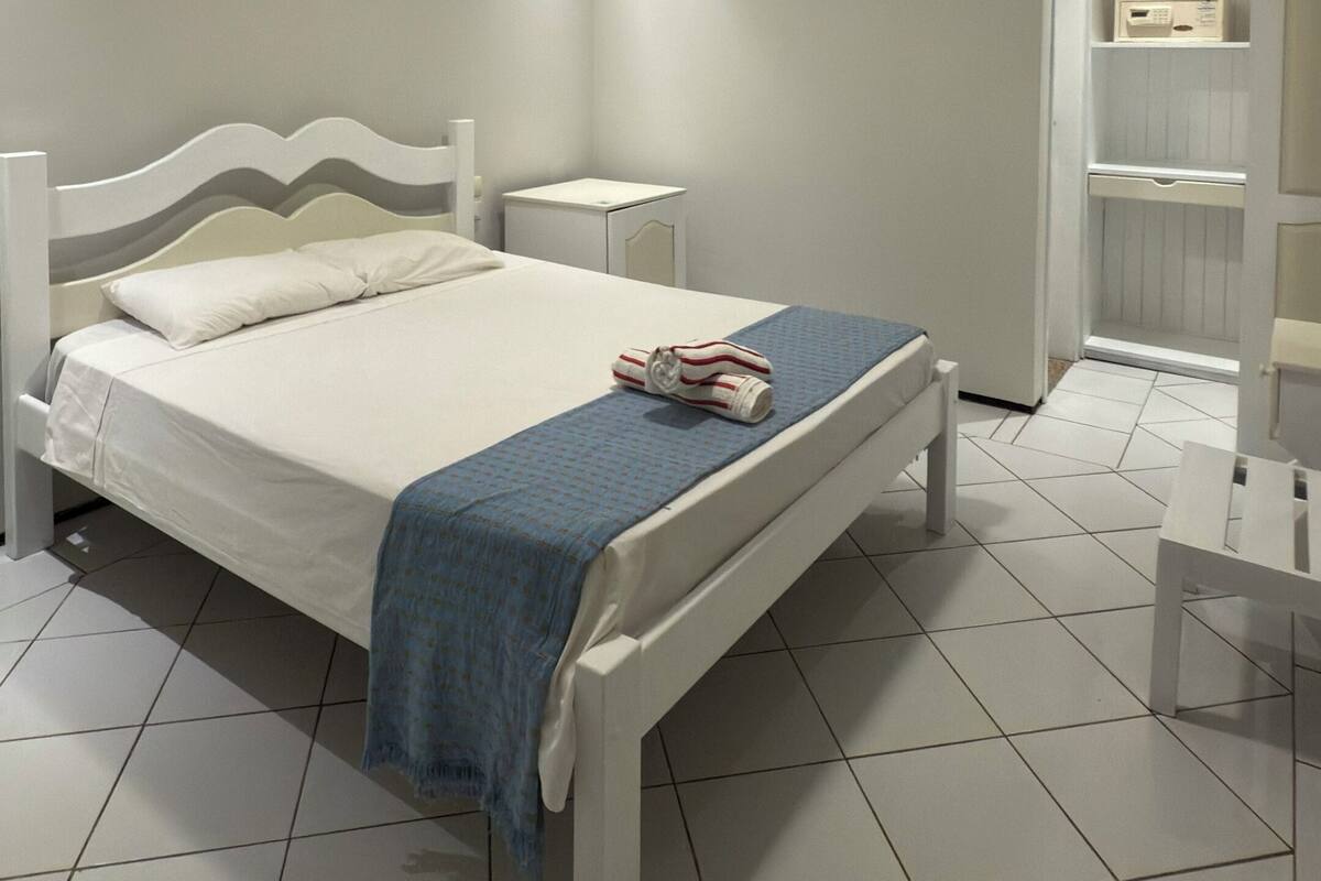 A bedroom with a bed, bedside tables, a wardrobe, and an air conditioning unit.