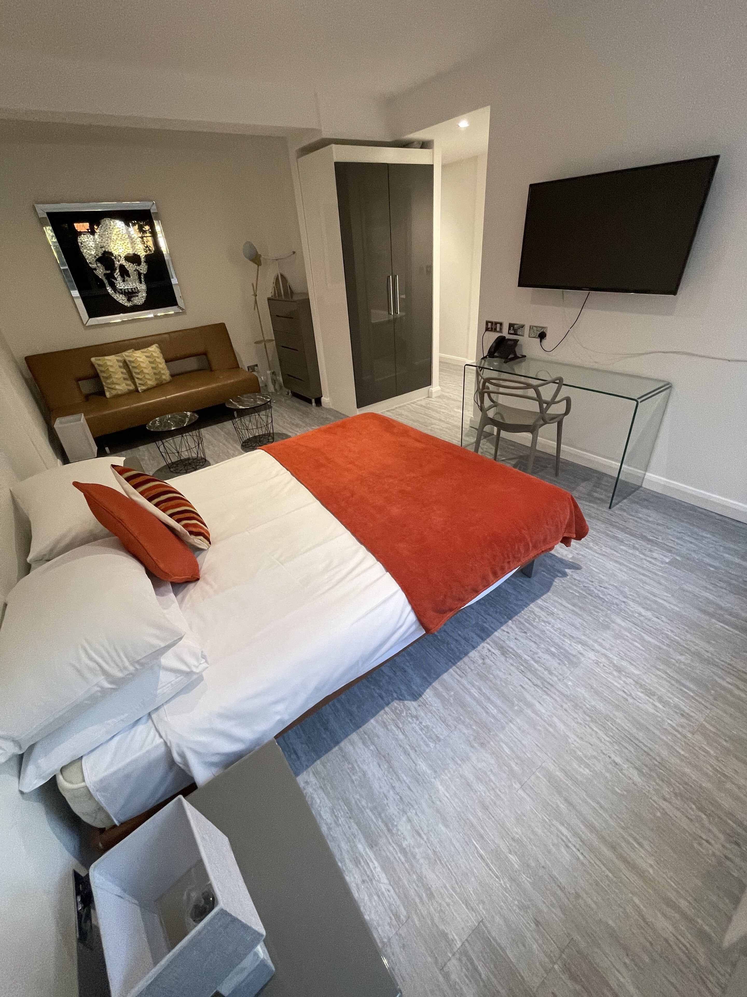 A modern hotel room with a large bed, a desk, a wardrobe, and a TV on the wall.