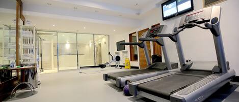 Une salle de sport moderne équipée de tapis de course, d’un vélo d’appartement et d’un rameur.