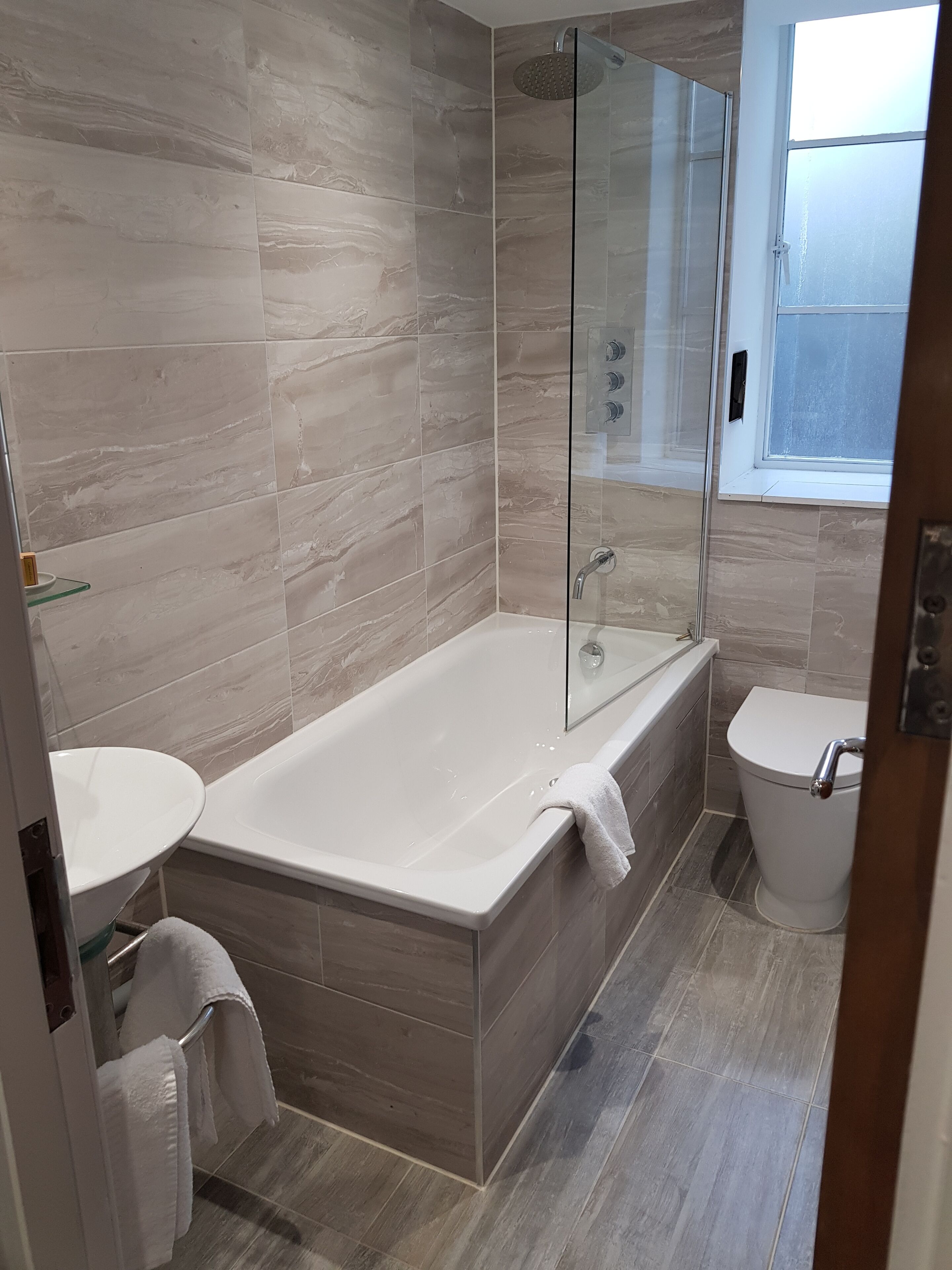 A modern bathroom with a glass-enclosed shower, a freestanding bathtub, and a toilet.