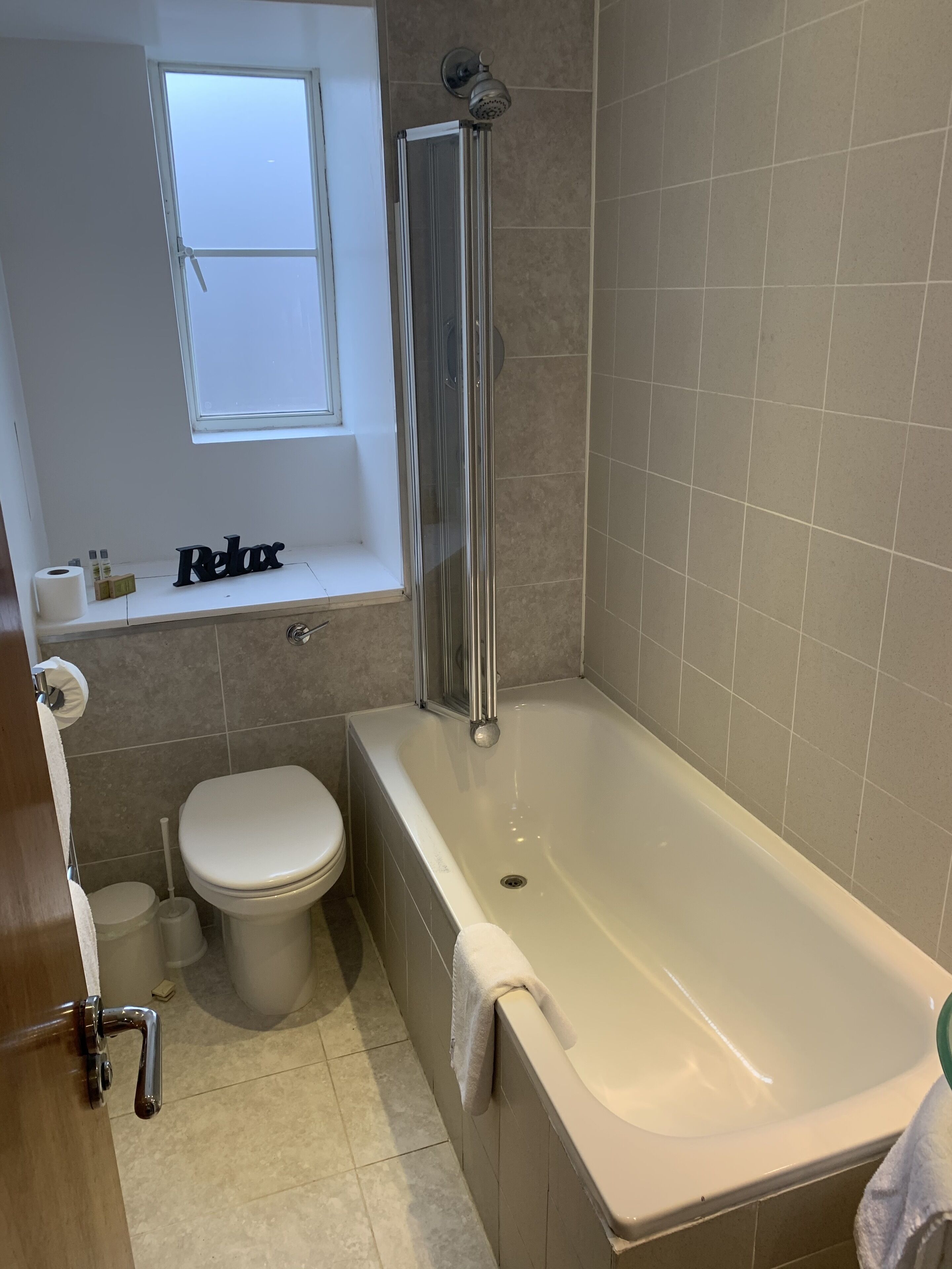 A bathroom with a bathtub, toilet, and a window above the toilet.