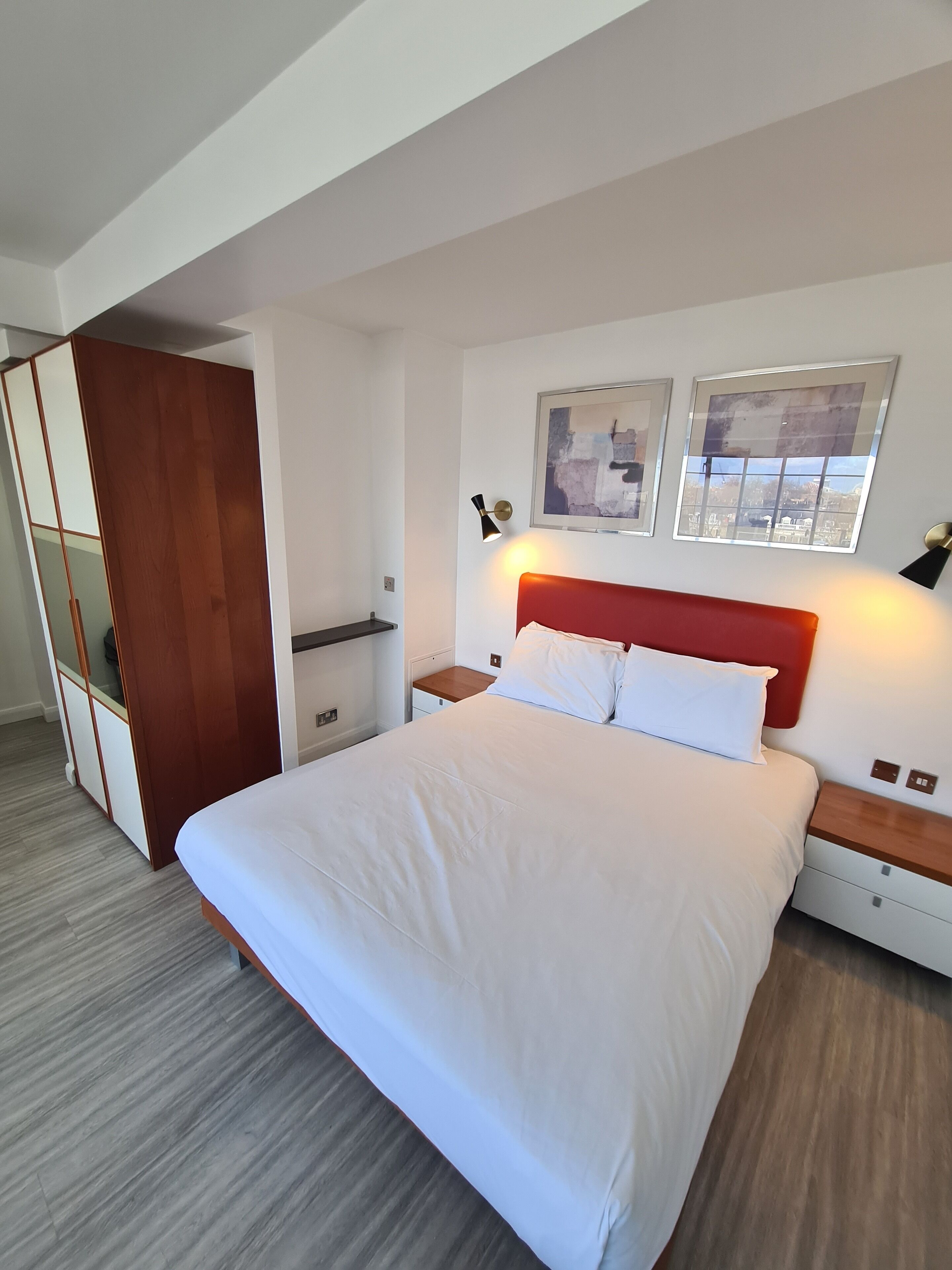 Una camera da letto moderna con un letto grande, un'armadiatura in legno e due lampade a parete.
