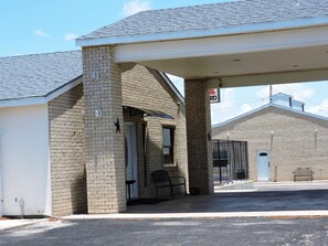 A gas station with a brick facade, a covered waiting area, and a visible gas pump.