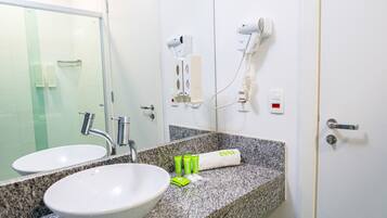 A bathroom with two sinks, a mirror, a hairdryer, and toiletries on the counter.