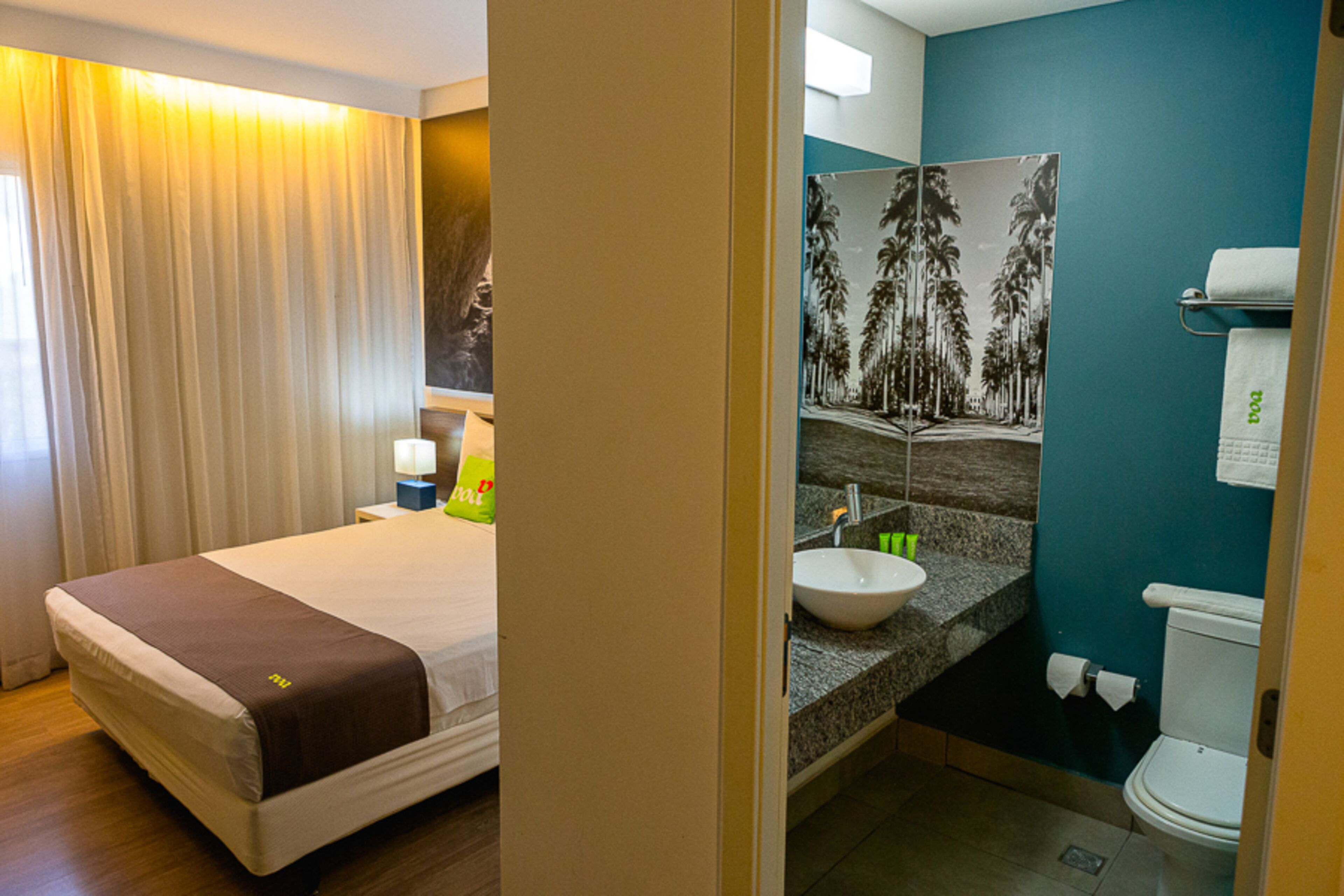 A hotel room with a bed, a bathroom with a sink, and a toilet.