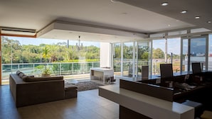 Een ruime, moderne woonkamer met een balkon met uitzicht op een weelderige tuin en een stadsgezicht.