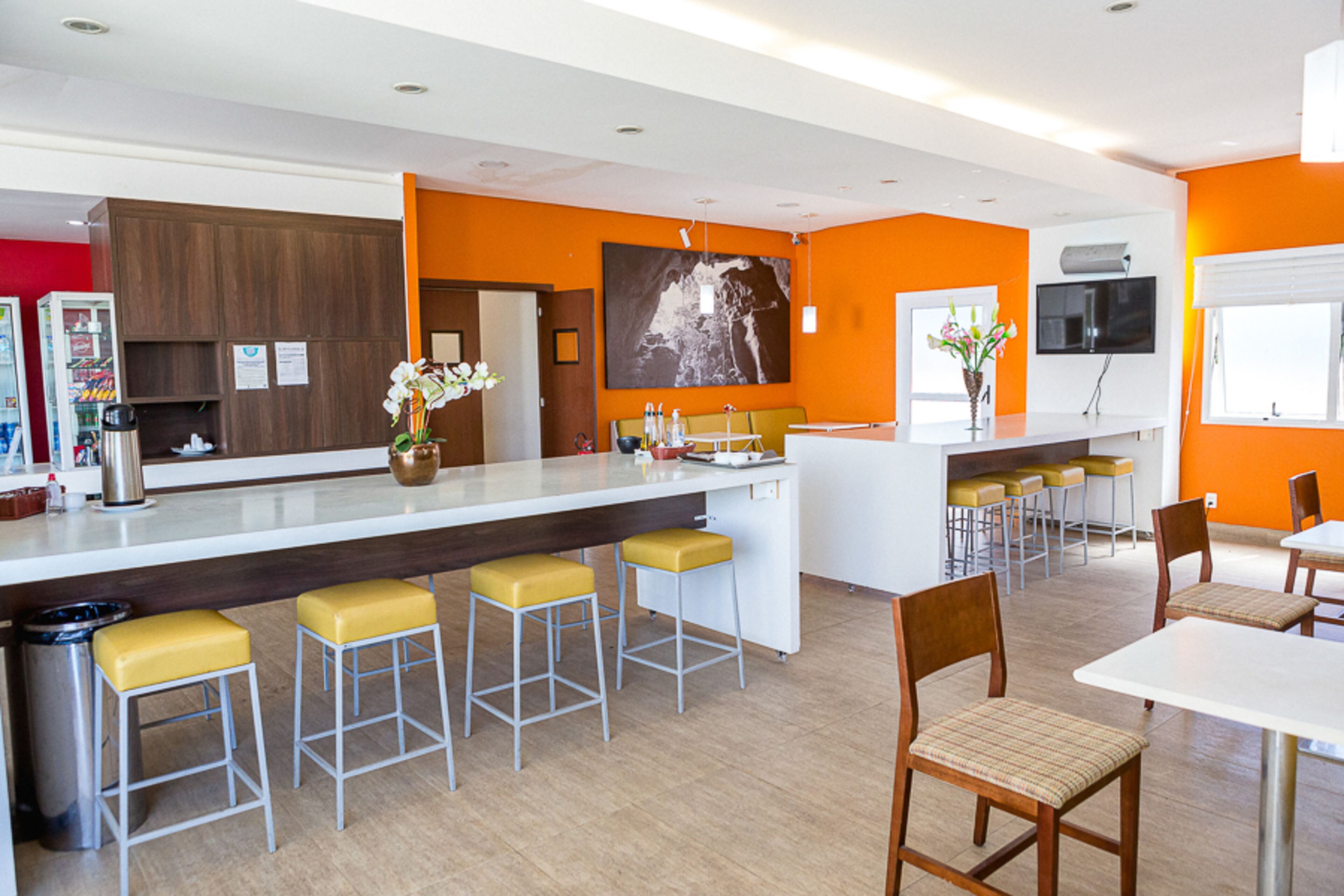 A modern kitchen with a central island, bar stools, and a dining area with chairs and tables.