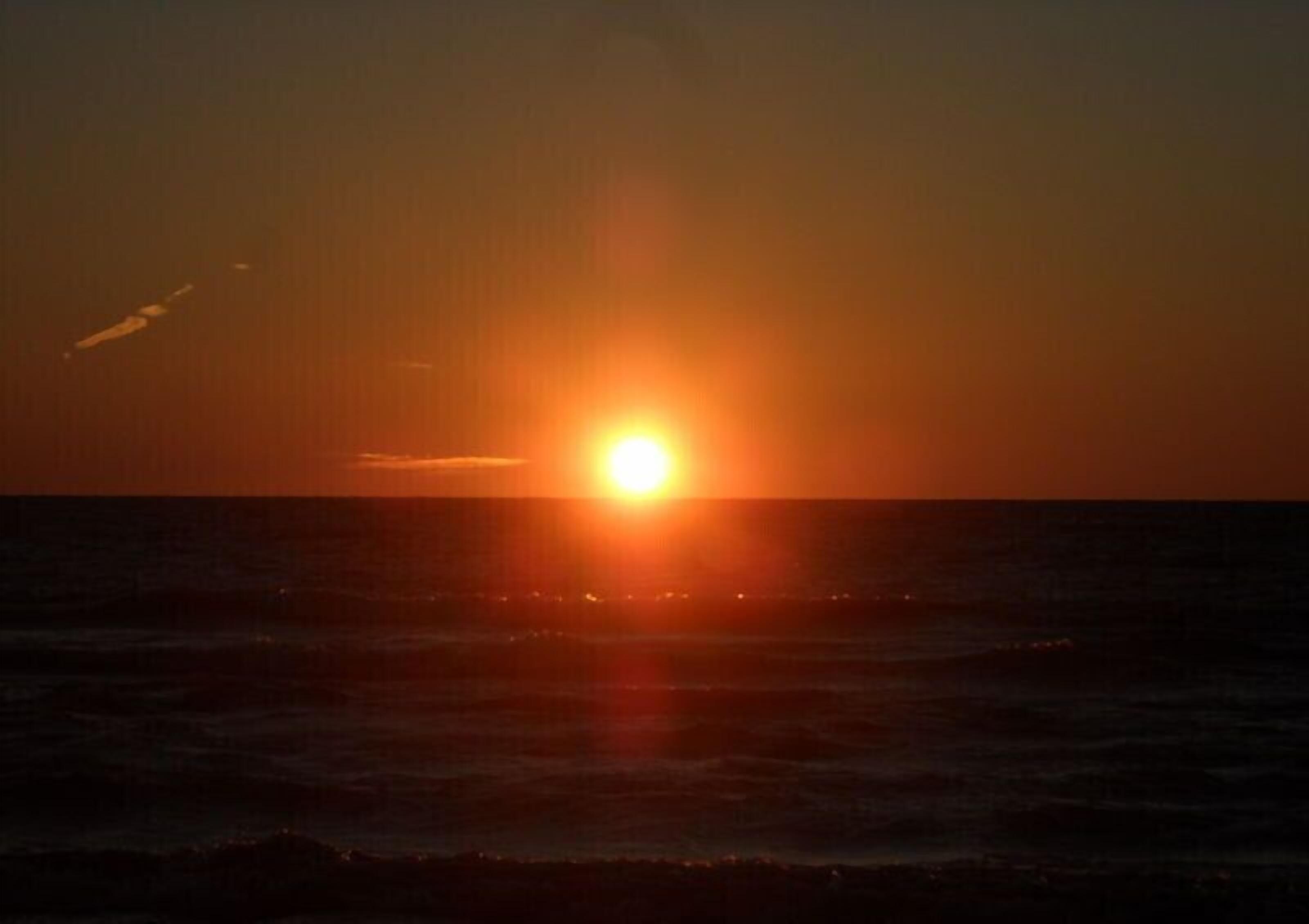 Tramonto sull'oceano, con il sole basso all'orizzonte.