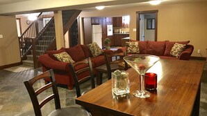 Zona pranzo con tavolo in legno, divani rossi e una scala che conduce a un'altra stanza.