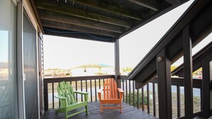 Une terrasse en bois avec deux chaises Adirondack donnant sur une étendue d’eau.