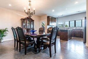 A dining area with a dark wooden table and chairs, a chandelier, and a large mirror. - Lake Travis Acreage with Hilltop Views (Austin)