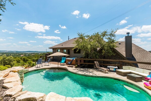 A backyard with a swimming pool, lounge chairs, and a hot tub. - Lake Travis Acreage with Hilltop Views (Austin)