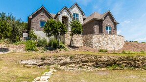 A large, multi-story house with a stone facade and multiple gabled roofs. - Lake Travis Acreage with Hilltop Views  (Austin)