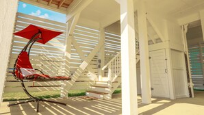 Un espacio al aire libre techado con una silla roja y una sombrilla, una escalera y una puerta blanca.