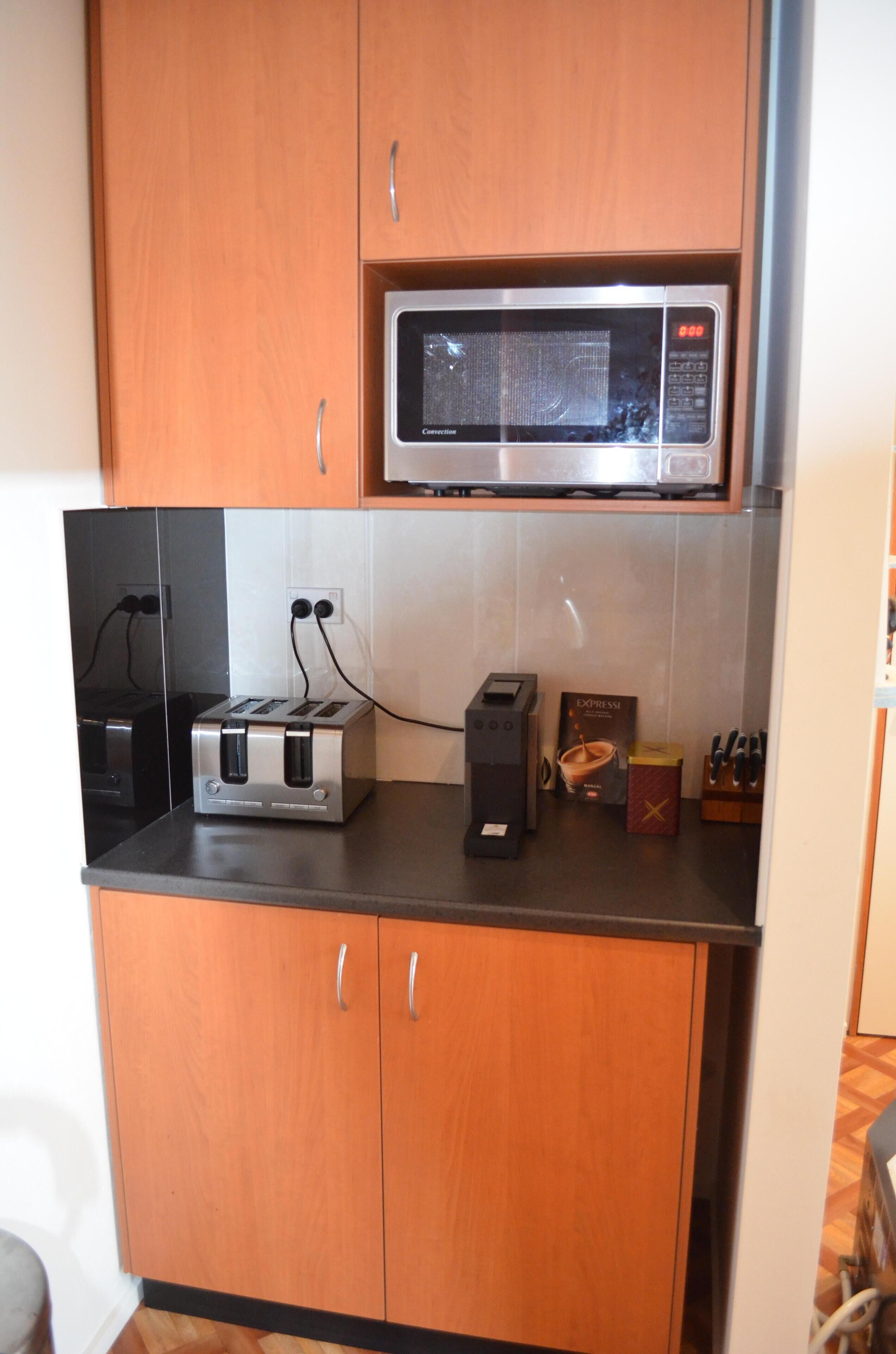A kitchen with wooden cabinets, a microwave, a toaster, and a coffee maker.