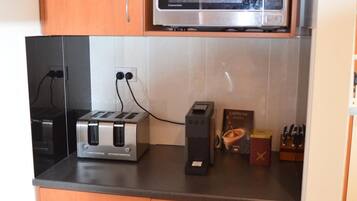 A kitchen with wooden cabinets, a microwave, a toaster, and a coffee maker.