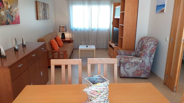 A compact living space with a sofa, a chair, a small table, and a wooden cabinet. - Tahiti- Spacious, Private Parking, Terrace with Sunbeds, 300 meters Beach (Quarteira)