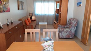 A compact living space with a sofa, a chair, a small table, and a wooden cabinet.