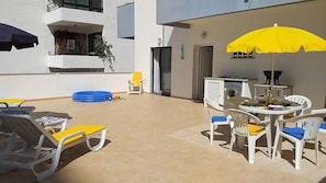 An outdoor patio with a table and chairs, a yellow umbrella, and a washing machine.