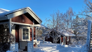 A wooden cabin with a snow-covered porch and a clear blue sky.