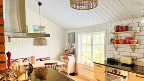 A modern kitchen with a central island, wooden cabinets, a Bosch oven, and a dining area with a table and chairs.